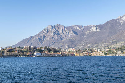 Scenic view of sea by mountain against sky