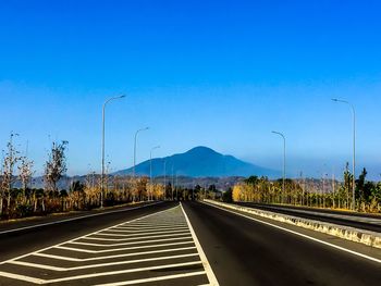 Empty road against clear blue sky