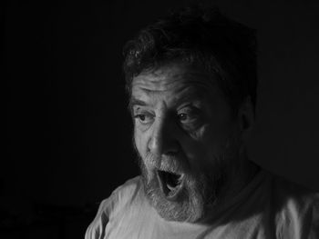 Close-up portrait of surprised man against black background