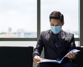 Man with mask sitting in waiting room in office