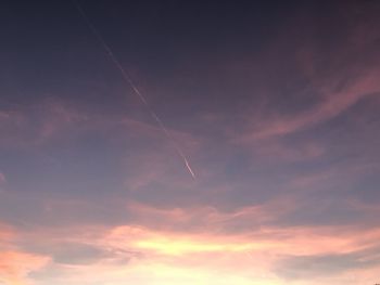 Low angle view of vapor trail in sky during sunset