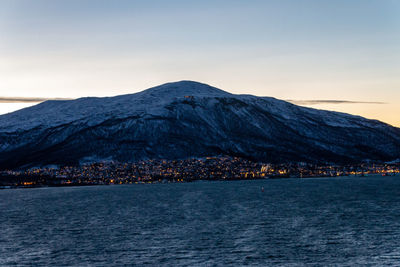 Scenic view of sea by snowcapped mountain against sky