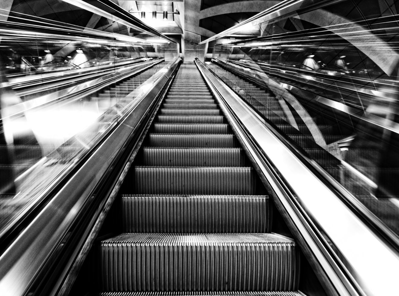 transportation, escalator, architecture, modern, built structure, indoors, illuminated, rail transportation, railroad track, diminishing perspective, public transportation, the way forward, railroad station, high angle view, city, vanishing point, travel, motion, railing, steps and staircases
