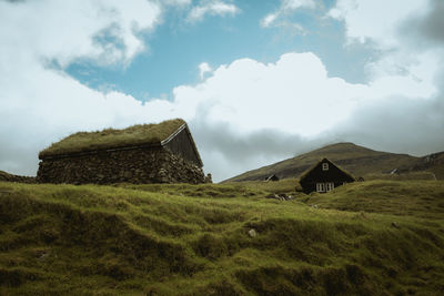 Built structure on landscape against cloudy sky