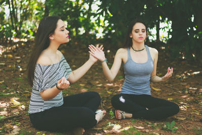 Friends meditating while sitting at park