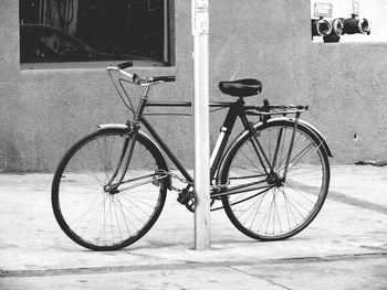 Bicycle parked by pole on footpath