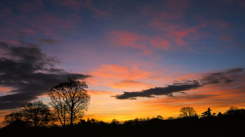 Low angle view of silhouette trees against dramatic sky