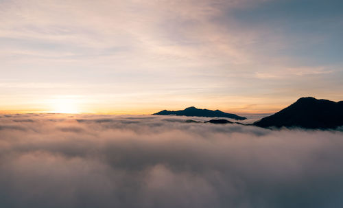 Scenic view of dramatic sky over silhouette mountains during sunset