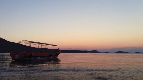 Ship in sea against clear sky during sunset