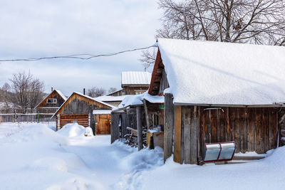 House on snow covered landscape against sky