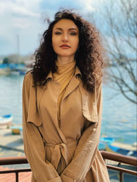 Portrait of beautiful young woman against water