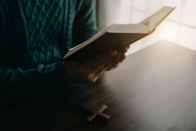 Midsection of man reading book at home