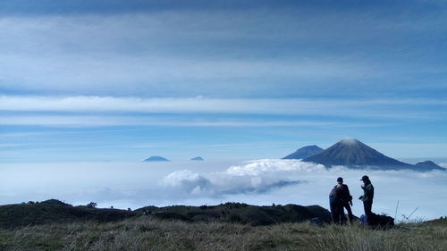 People standing against mountain and cloudy sky