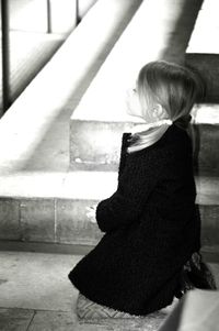 Side view of girl praying while kneeling on floor