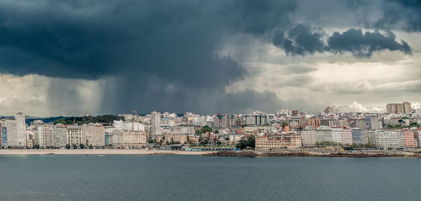 Panoramic view of city by sea against sky