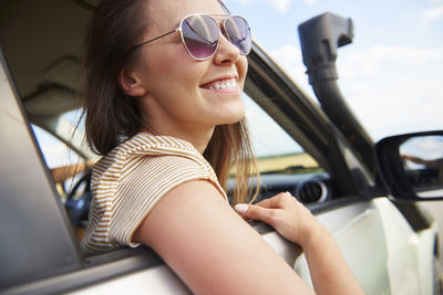 Smiling woman wearing sunglasses in car