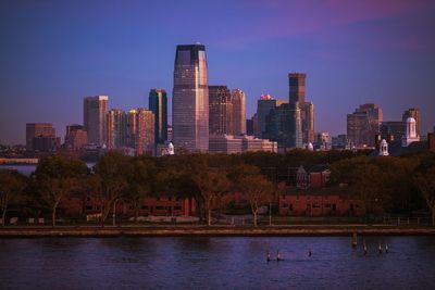 River by cityscape against clear blue sky