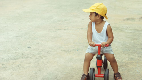 Full length of baby boy riding toy bicycle