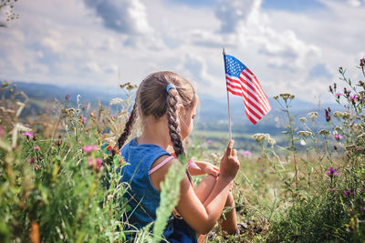 National flag day celebration. little patriot sitting on meadow and holding national flag of usa