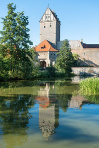 Medieval citywall with tower  by moat as reflection  against sky