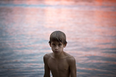 Boy by lake at sunset