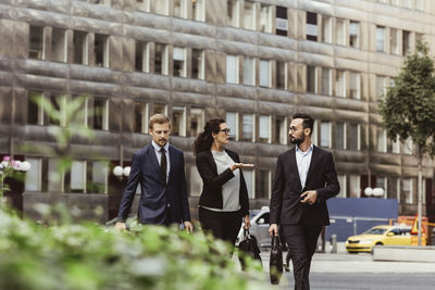 Female entrepreneur discussing business strategy with male colleagues while walking outdoors