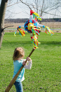 Young girl swings a base ball bat at a colorful pinata