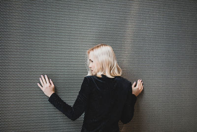 Rear view of woman standing against wall