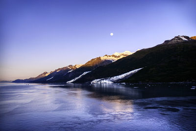 Scenic view of lake and snowcapped mountains against clear blue sky