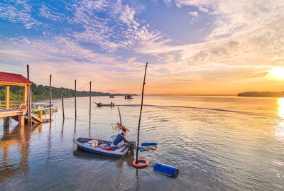 People on sea against sky during sunset