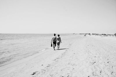 Rear view of people walking on beach