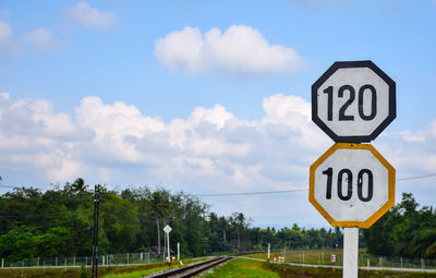 Road sign on field against sky