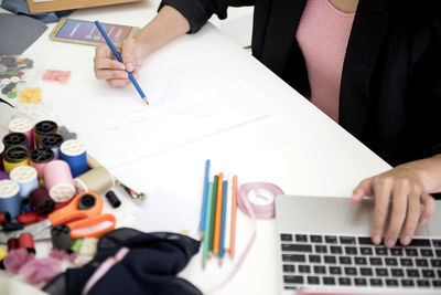 Midsection of woman using laptop on desk in office