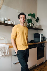 Portrait of confident mid adult man standing in kitchen at home