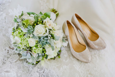 High angle view of roses with shoes on wedding dress