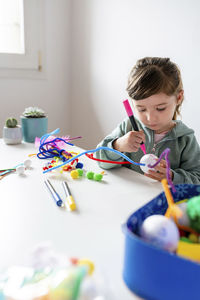 Girl holding multi colored toys on table