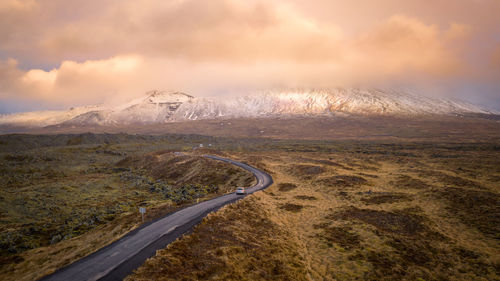 Road by landscape against cloudy sky