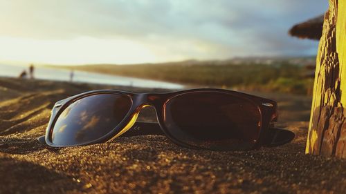 Close-up of sunglasses against sky on beach