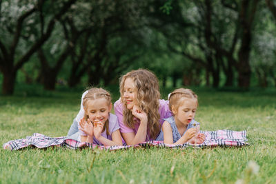 Mom and her daughters are lying on the beach in a summer park. the family has fun outdoors