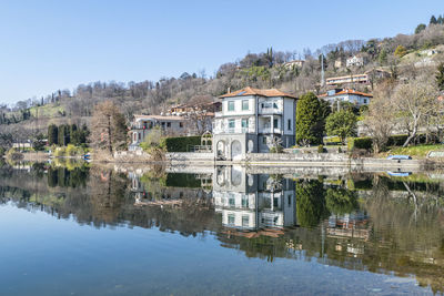 Houses and plants are reflected in the water of lake pusiano