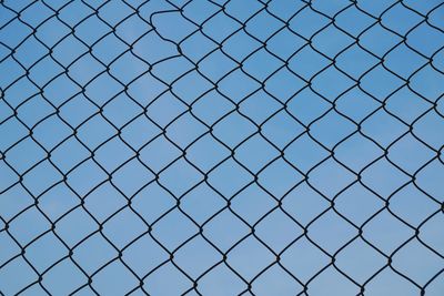 Full frame shot of chainlink fence against blue sky