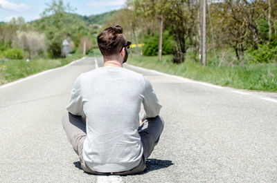 Rear view of man sitting on road