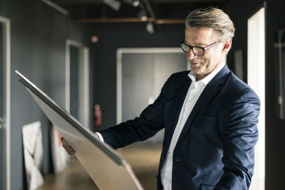 Mature businessman in office looking at painting