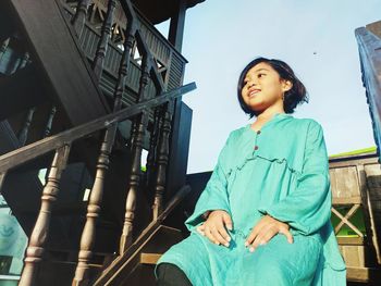 Low angle view of woman standing by railing against sky