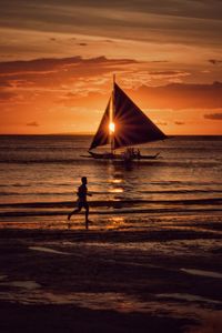 Silhouette people on beach against sky during sunset