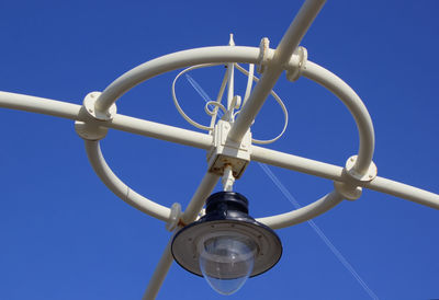 Low angle view of lighting equipment against clear blue sky