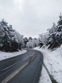 Road amidst snow covered trees against sky