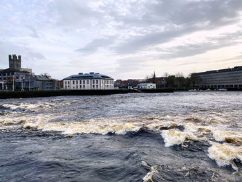 Sea by buildings against sky in city