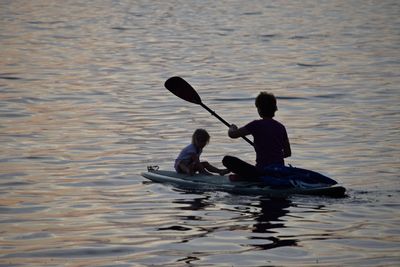 Mother and daughter sitting on boat in sea during sunset