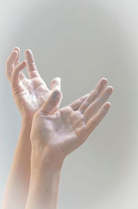 Cropped image of woman hands gesturing against gray background